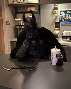 a batman costume sitting on top of a counter next to a cup