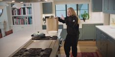 a woman standing in a kitchen holding a paper bag