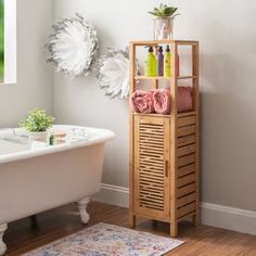 a white bath tub sitting next to a wooden shelf filled with flowers on top of it