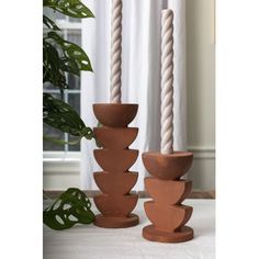 three clay candlesticks sitting on top of a table next to a potted plant