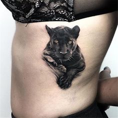 a woman's stomach with a black cat tattoo on it