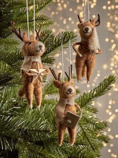 three ornaments hanging from a christmas tree with lights in the background and deers on them