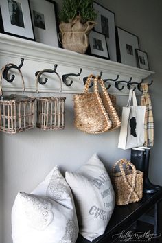 some baskets are hanging on the wall above a bench with pillows and other items in front of them