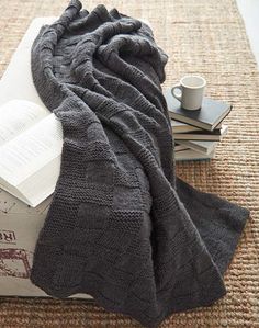 a pile of books sitting on top of a rug next to a cup and book