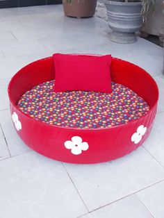 a red dog bed with flowers on the bottom and a pillow in the middle that is made out of plastic