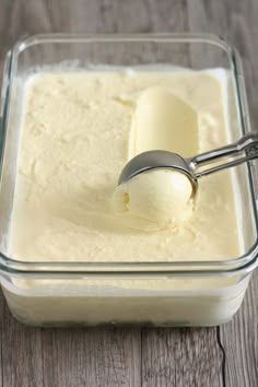 a scoop of vanilla ice cream in a glass bowl with a metal spoon on the side