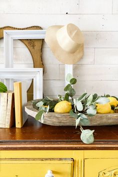 a yellow dresser with lemons on it and a hat sitting on top of it