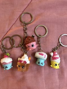 four different keychains with small toys on them sitting on a pink cloth covered surface