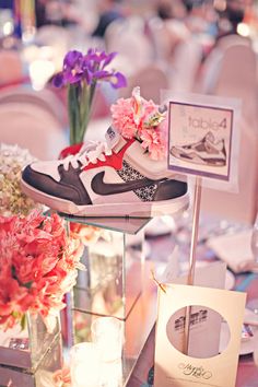 a pair of sneakers sitting on top of a table with flowers in vases and cards