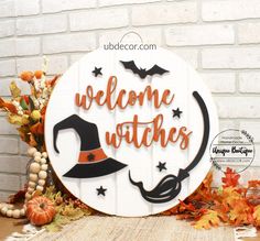 a welcome sign with a witch's hat and broom in the center surrounded by fall leaves