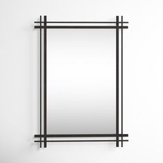 a mirror hanging on the wall next to a shelf with a black frame and metal bars