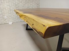 a wooden table with black metal legs and a brick wall in the backround