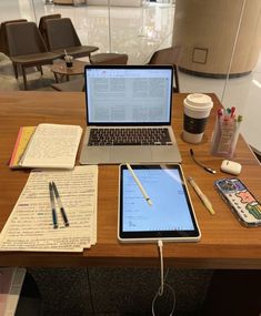 an open laptop computer sitting on top of a wooden desk next to a cup of coffee