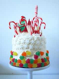 a birthday cake with white frosting and candy canes on top, decorated with multi - colored candies