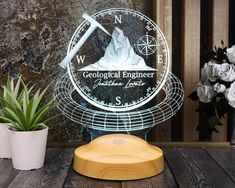 a glass clock with an image of a mountain on it and a plant in the foreground