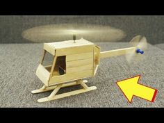 a wooden toy helicopter sitting on top of a carpeted floor next to an arrow