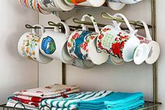 a rack with cups and saucers on it next to a wall mounted towel rack