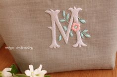 a close up of a pillow on a table with flowers and a flower pot in the background