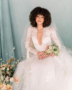 a woman in a wedding dress sitting next to flowers