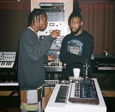 two men standing next to each other in front of an electronic mixing desk with sound equipment