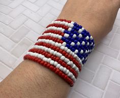 an american flag bracelet on someone's arm with red, white and blue beads