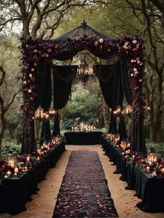 an outdoor ceremony with candles and flowers on the aisle, decorated in black linens