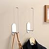 a coat rack with two coats hanging from it's hooks and a mirror on the wall