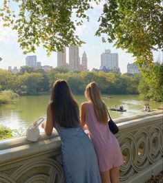 two girls looking out over the water from a bridge in central park, new york city