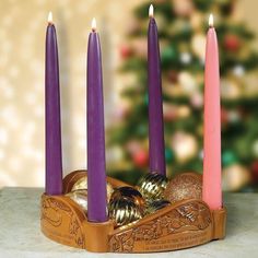 three candles in a wooden holder with ornaments