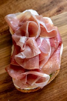 a sandwich with ham on it sitting on top of a wooden table