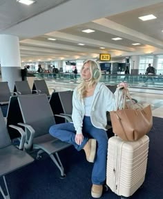 a woman sitting in an airport with her luggage