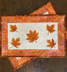 two quilted placemats with maple leaves on them