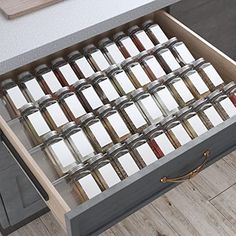 an open drawer filled with lots of jars and spices on top of a wooden floor