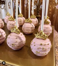 some pink cake pops with gold decorations on them