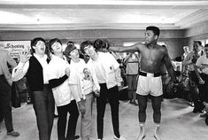 a group of people standing around each other in front of a man with boxing gloves on