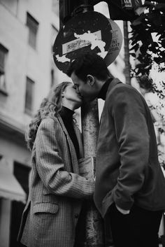 a man and woman kissing next to a street sign