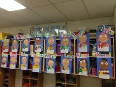 many children's artwork is displayed on the wall in front of bookshelves