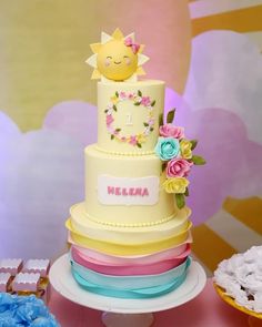 there is a three tiered cake with flowers on the top and a sun decoration