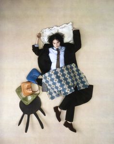 a man laying on top of a bed covered in pillows and blankets next to other items