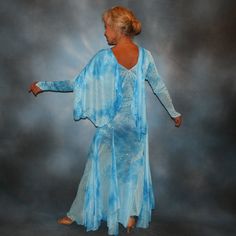 a woman in a blue dress is dancing with her arms spread out to the side