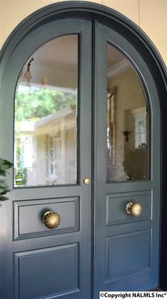 a blue double door with two sidelights and arched glass panels on the front entrance