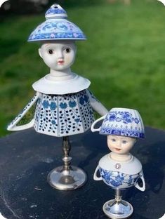 two porcelain figurines sitting on top of a black table next to each other