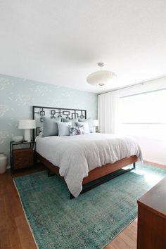 a large bed sitting on top of a wooden floor next to a window in a bedroom