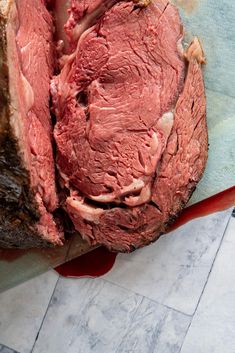 a large piece of meat sitting on top of a cutting board next to a knife