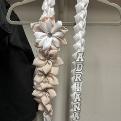 two white and beige flower hair ties on a hanger next to a black shirt