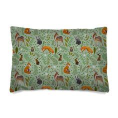 a green and orange pillow with deers on the front, surrounded by plants and leaves