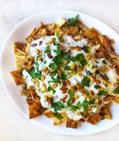 a white plate topped with nachos covered in ranch dressing