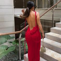 a woman in a red dress is walking down the stairs with her back turned to the camera