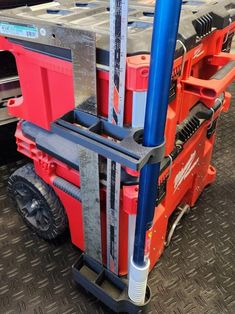 there is a red forklift with blue handles on the floor next to other trucks