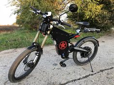 a black and red bike parked on the side of a road next to some trees